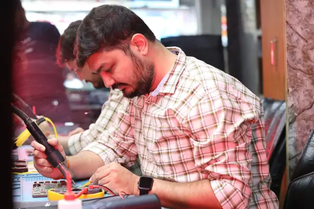 Technician soldering on a circuit board at the repair bench