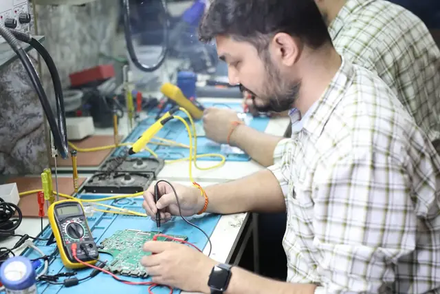 Technician soldering on a circuit board at the repair bench