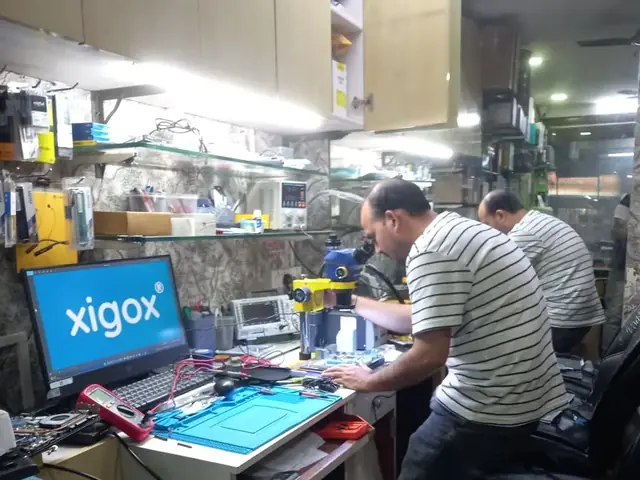Xigox technician at the repair bench working on a computer board