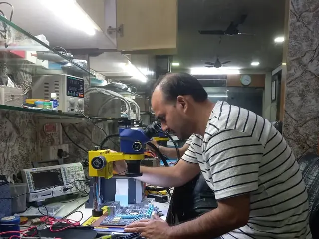 Technician inspecting a laptop motherboard under a microscope at the repair bench