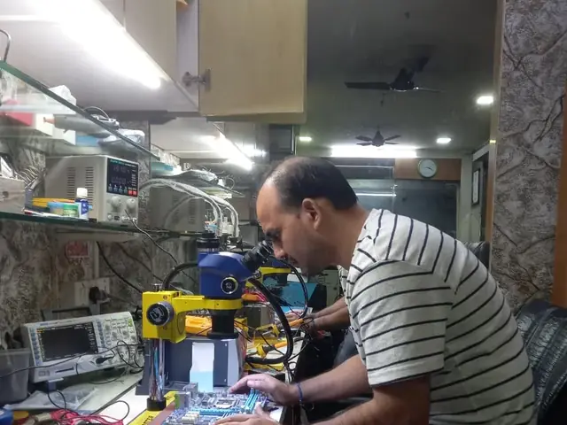 Technician inspecting a laptop motherboard under a microscope at the repair bench