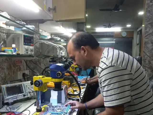 Technician inspecting a laptop motherboard under a microscope at the repair bench