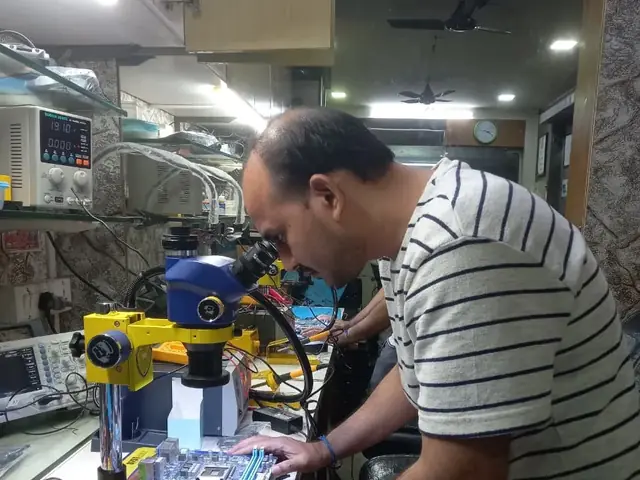 Technician inspecting a laptop motherboard under a microscope at the repair bench