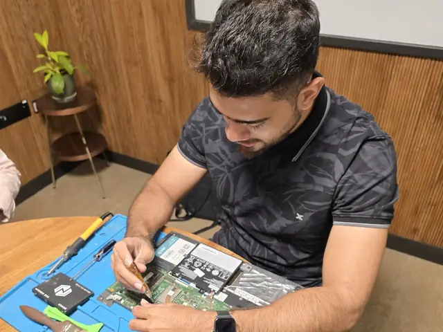 Technician working on an opened laptop with SSDs and tools laid out on an anti-static repair mat