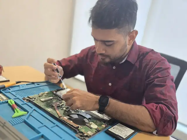 Technician working inside an opened laptop with RAM modules and an SSD laid out beside it
