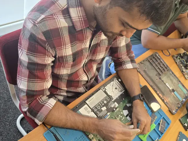 Top-down view of a technician servicing a laptop beside an SSD and a cleaning brush