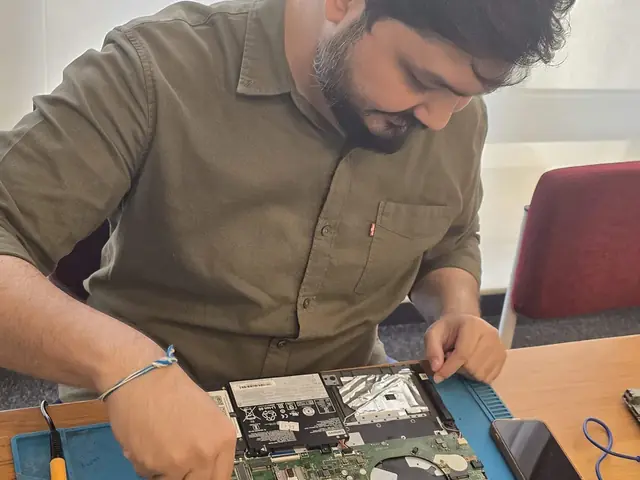 Technician working on an opened laptop with hard drives laid out on the repair mat
