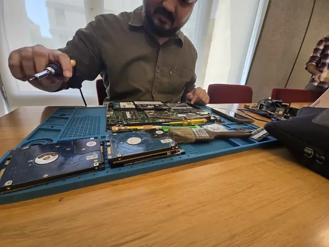 Technician working on an opened laptop with hard drives laid out on the repair mat
