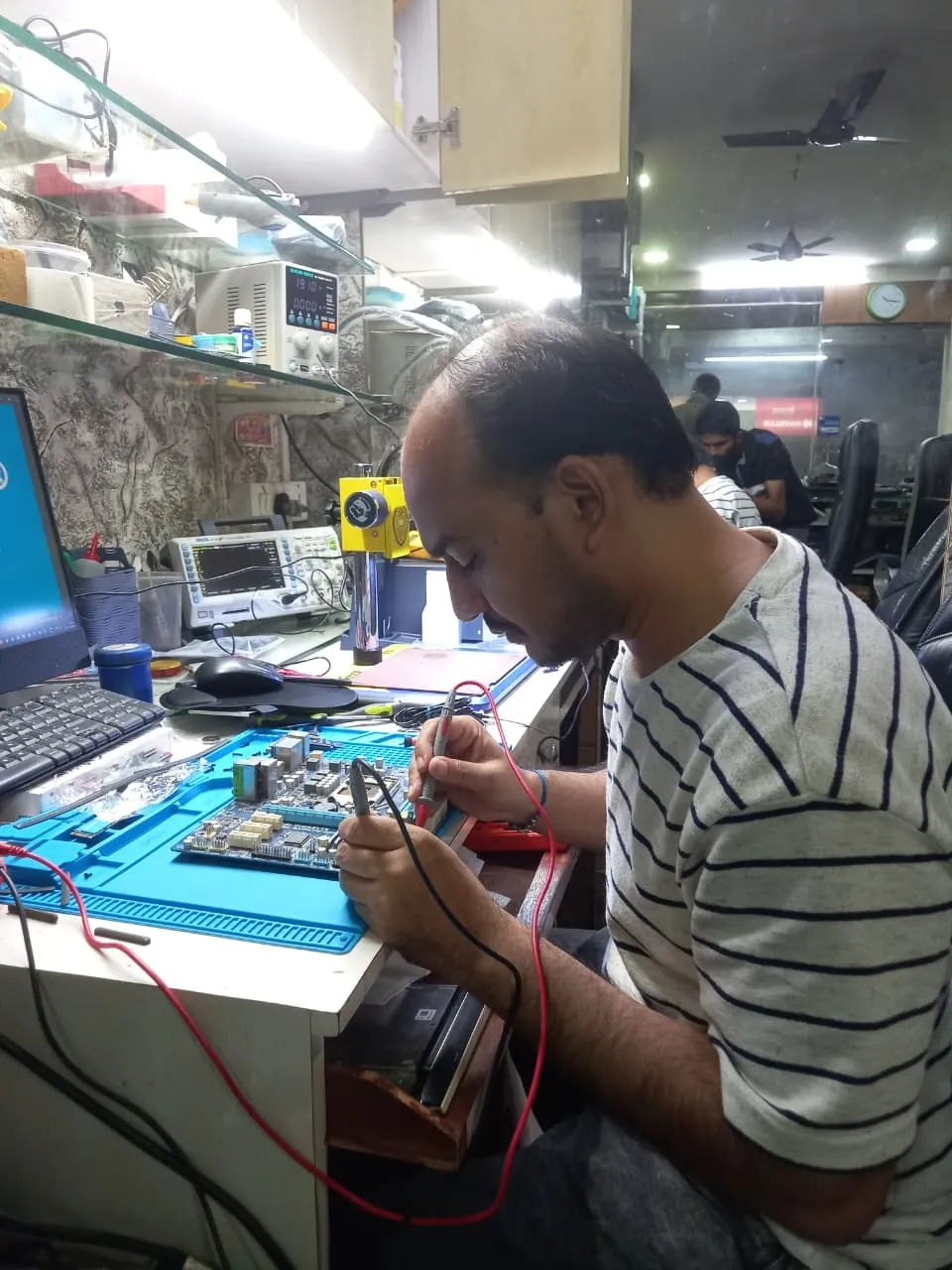 Xigox technician working on a laptop board at the Virar West repair workshop (photo 4)