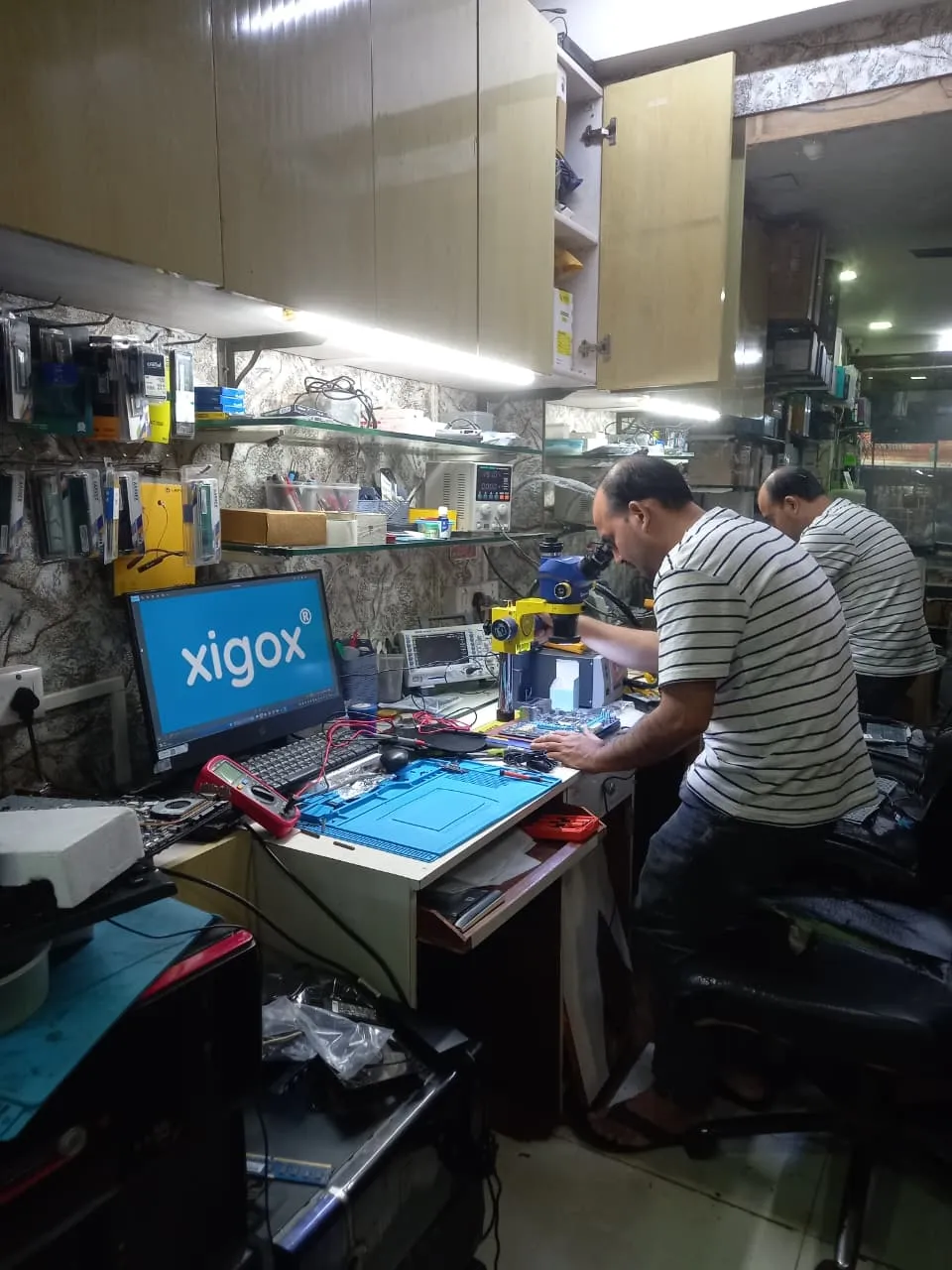 Xigox technician working on a laptop board at the Virar West repair workshop (photo 5)