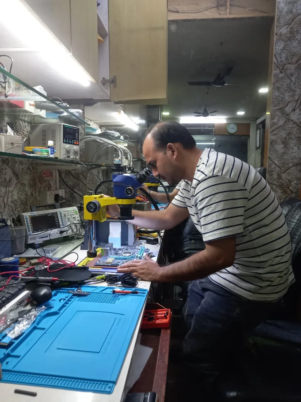 Xigox technician working on a laptop board at the Virar West repair workshop (photo 8)