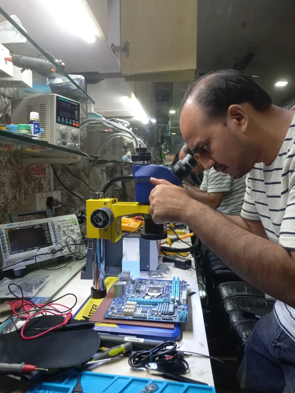 Xigox technician working on a laptop board at the Virar West repair workshop (photo 10)
