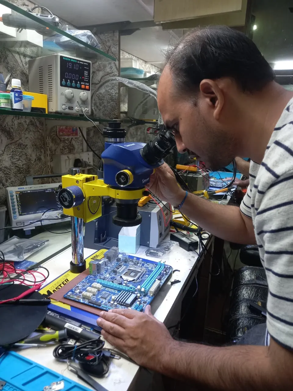 Xigox technician working on a laptop board at the Virar West repair workshop (photo 12)