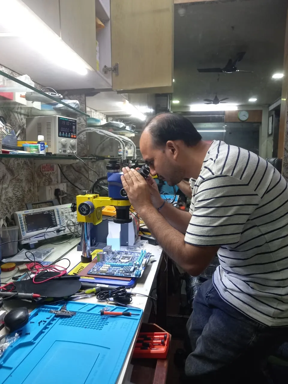 Xigox technician working on a laptop board at the Virar West repair workshop (photo 6)