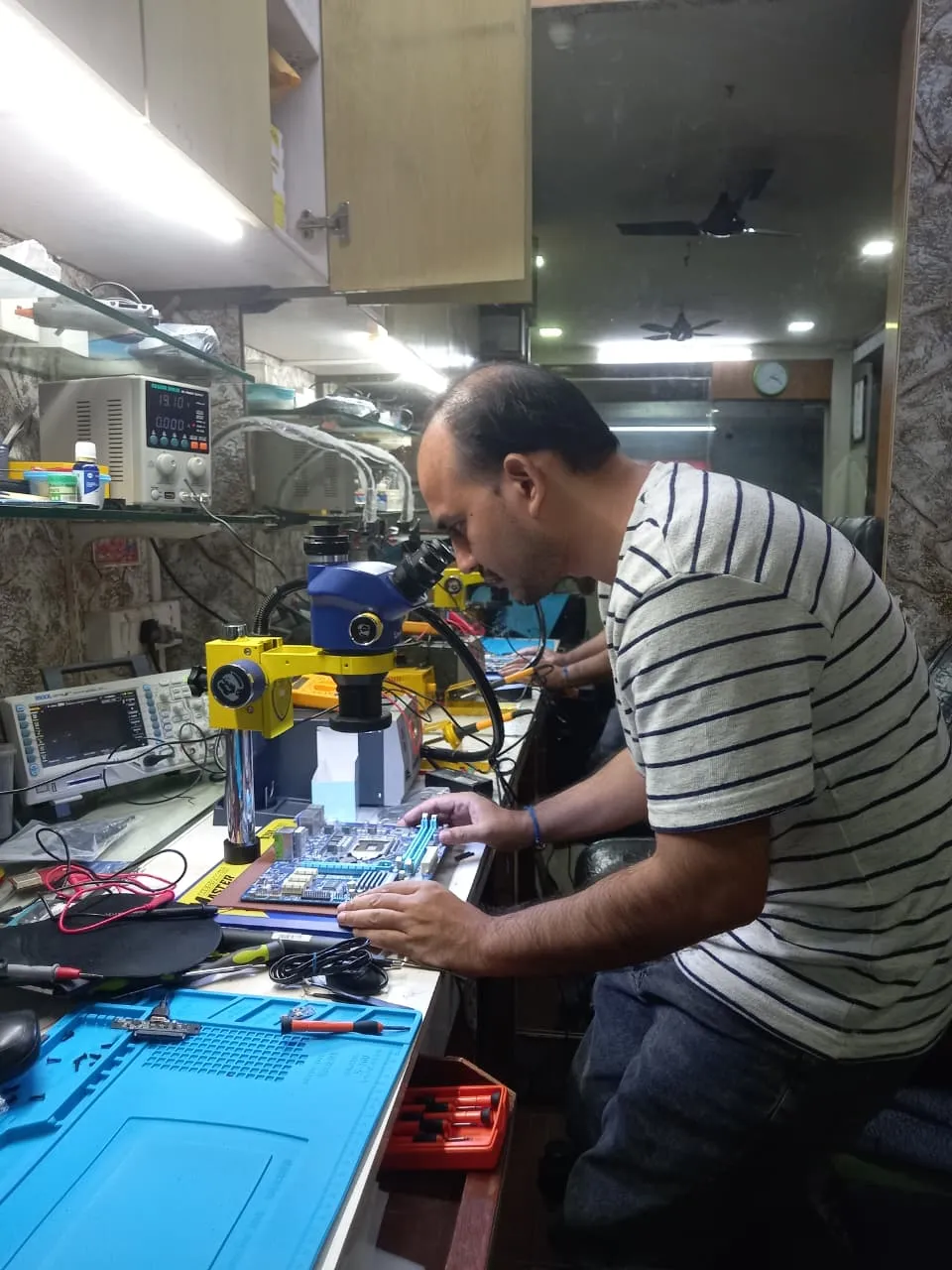 Xigox technician working on a laptop board at the Virar West repair workshop (photo 7)