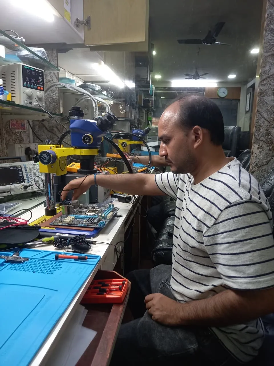 Xigox technician working on a laptop board at the Virar West repair workshop (photo 8)