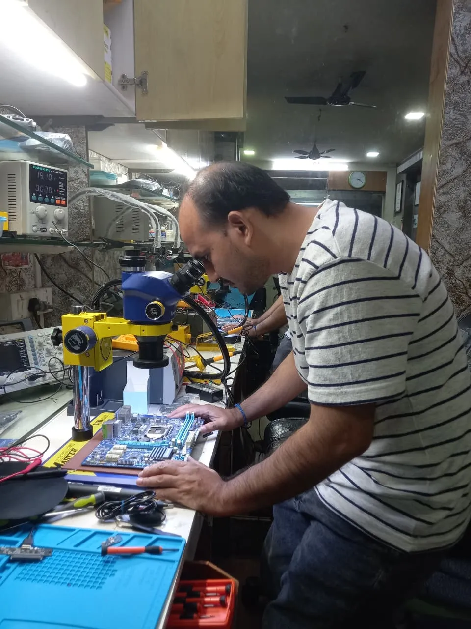 Xigox technician working on a laptop board at the Virar West repair workshop (photo 1)
