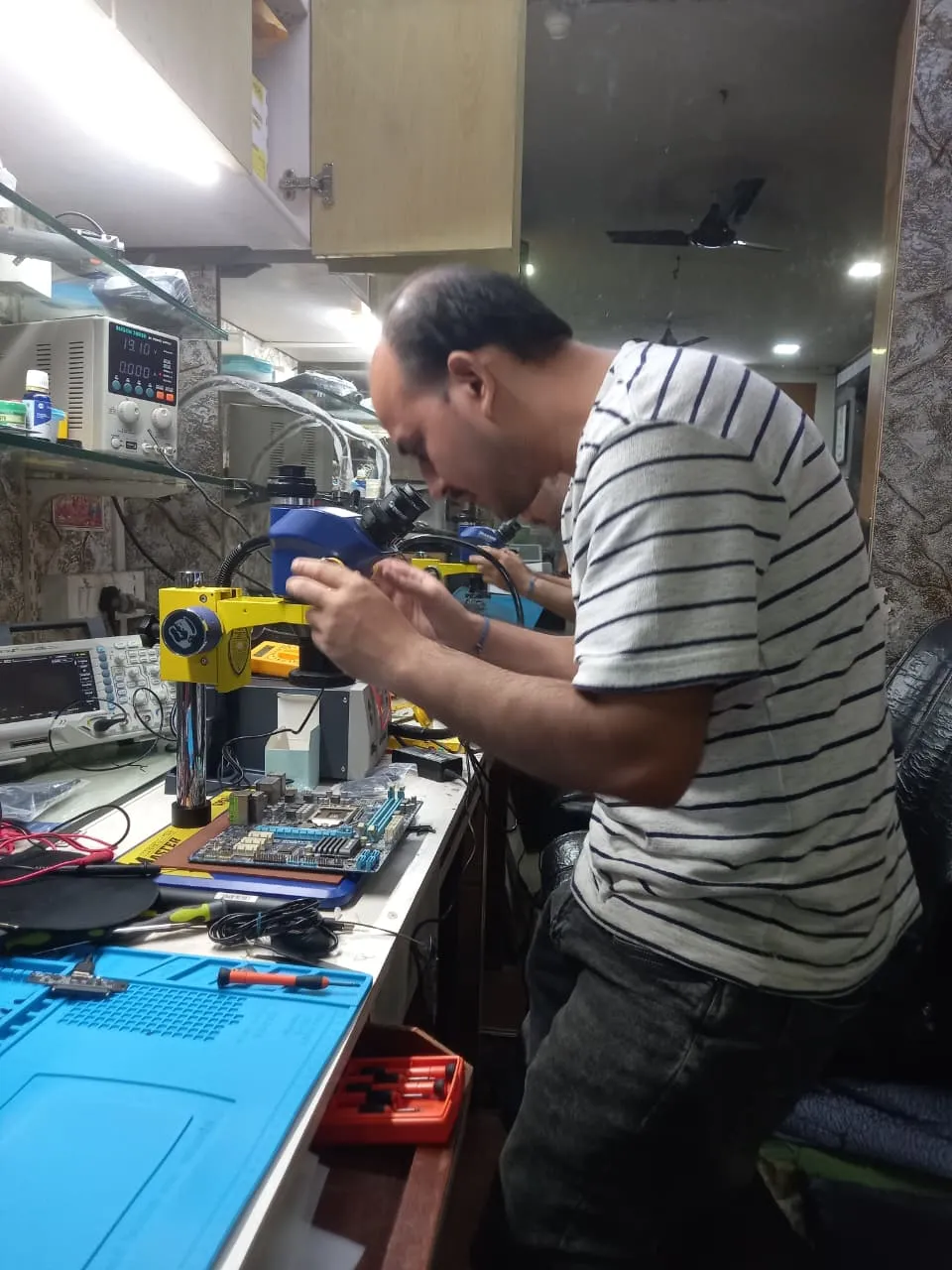 Xigox technician working on a laptop board at the Virar West repair workshop (photo 3)