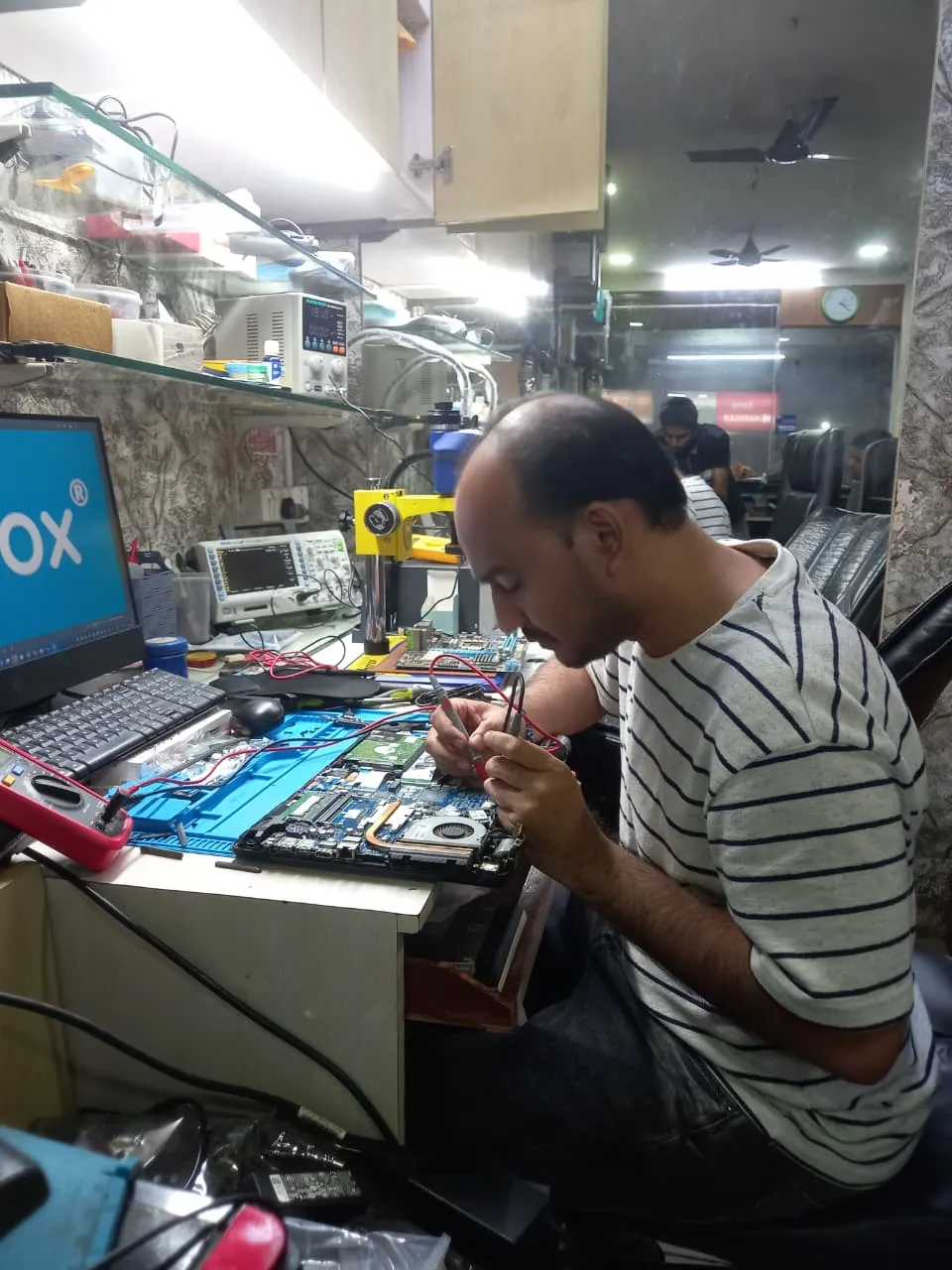 Xigox technician working on a laptop board at the Virar West repair workshop (photo 4)