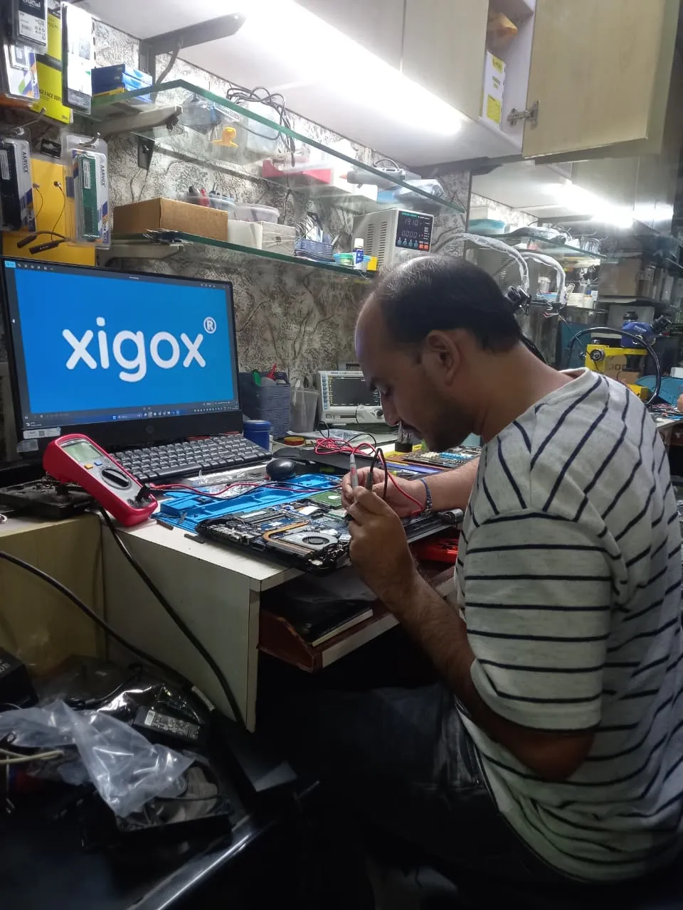 Xigox technician working on a laptop board at the Virar West repair workshop (photo 5)