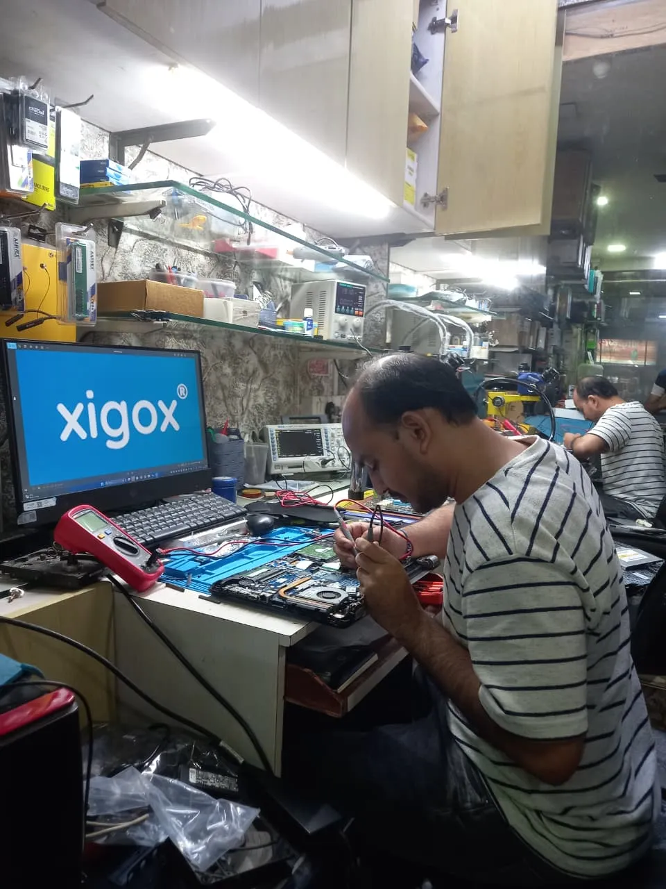 Xigox technician working on a laptop board at the Virar West repair workshop (photo 6)