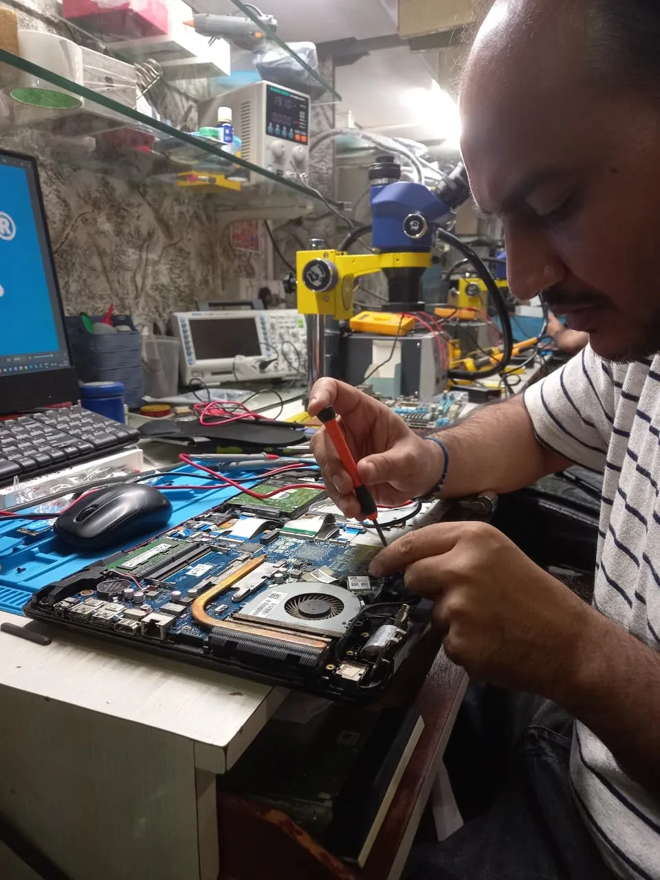 Xigox technician working on a laptop board at the Virar West repair workshop (photo 8)