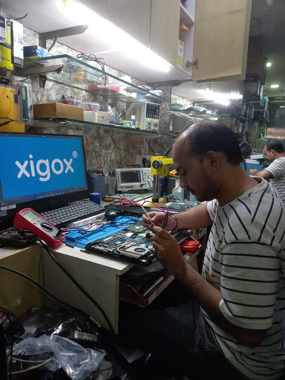 Xigox technician working on a laptop board at the Virar West repair workshop (photo 9)