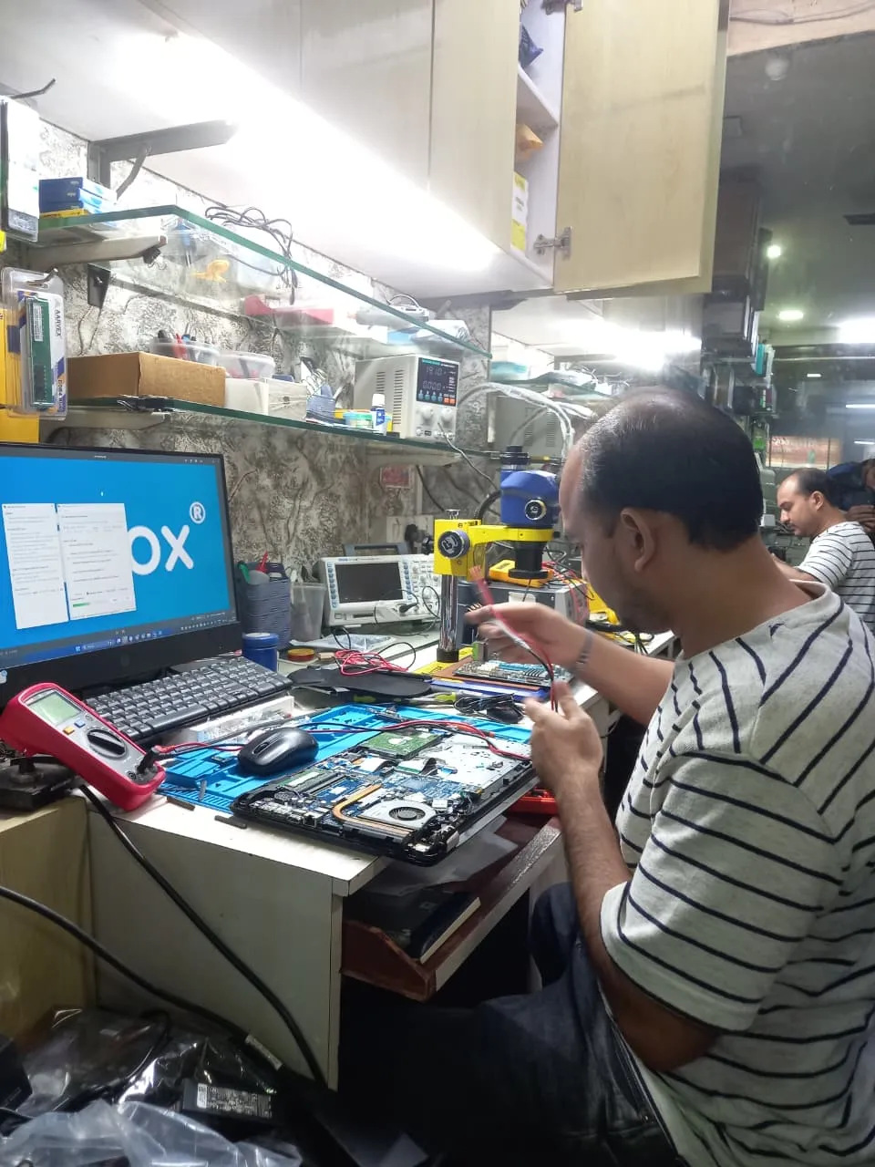 Xigox technician working on a laptop board at the Virar West repair workshop (photo 10)