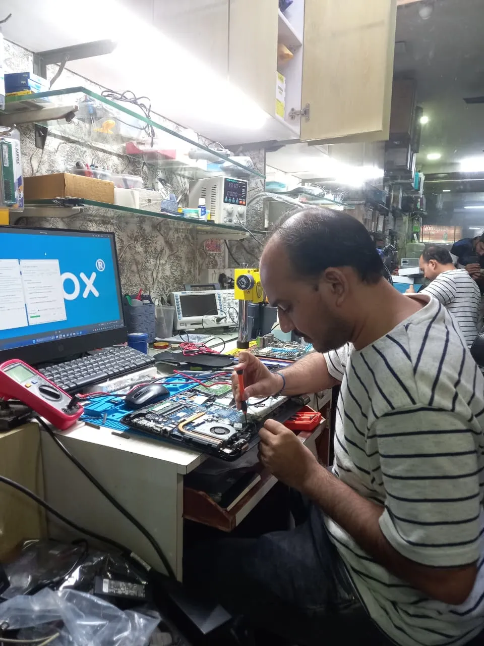 Xigox technician working on a laptop board at the Virar West repair workshop (photo 11)