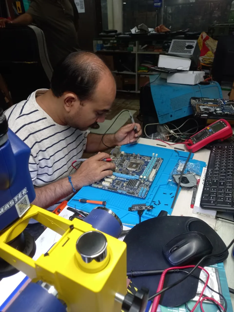 Xigox technician working on a laptop board at the Virar West repair workshop (photo 12)
