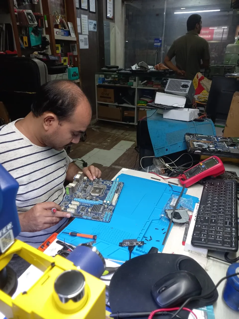 Xigox technician working on a laptop board at the Virar West repair workshop (photo 12)
