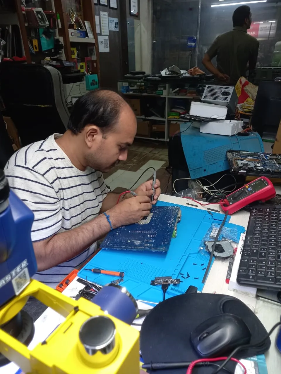 Xigox technician working on a laptop board at the Virar West repair workshop (photo 5)