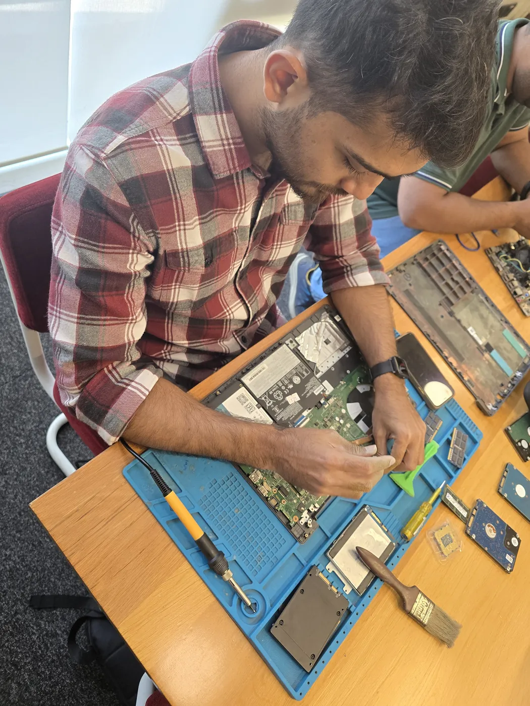 Top-down view of a technician servicing a laptop beside an SSD and a cleaning brush